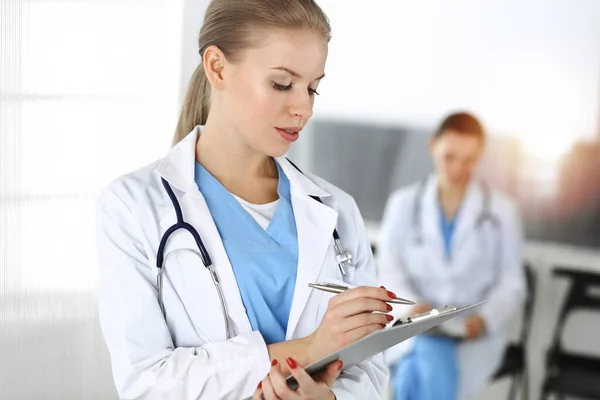 여성 - 의사는 임상 기록을 작성하기 위해 클립 보드를 사용하고 있습니다. — 스톡 사진