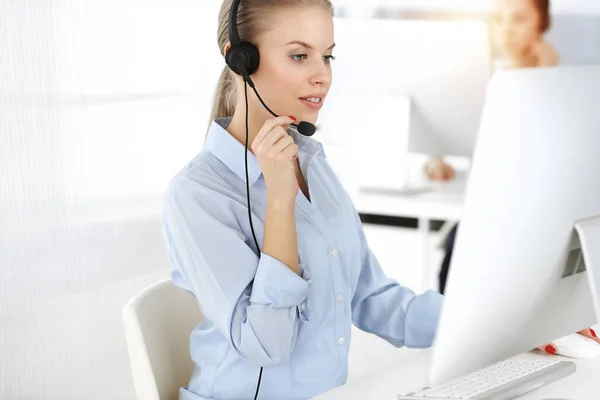 Blond woman working in sunny call center. Group of diverse people working as customer service occupation. Business concept — Stock Photo, Image