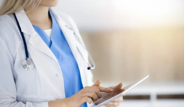 Άγνωστη γυναίκα-γιατρός στέκεται στην ηλιόλουστη κλινική και χρησιμοποιώντας το tablet pc, κοντινό πλάνο. Δεδομένα και καλύτερη εξυπηρέτηση στην ιατρική — Φωτογραφία Αρχείου