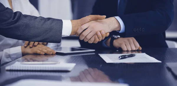 Handshake as successful negotiation ending, close-up. Unknown business people shaking hands after contract signing in modern office