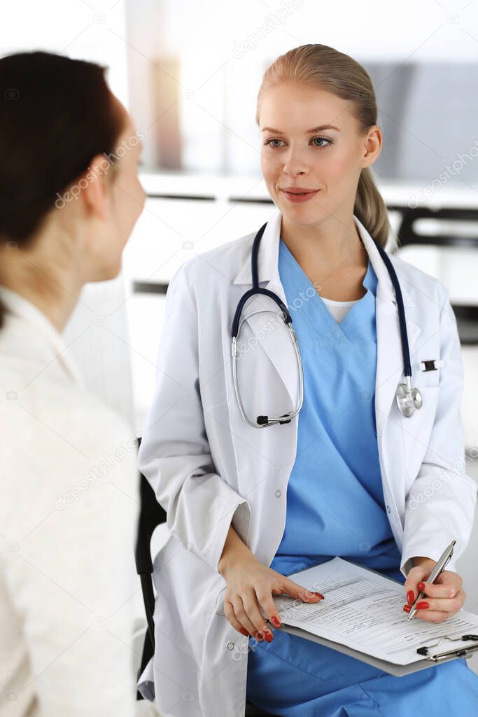 Woman - doctor consults her female patient in sunny clinic