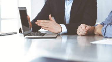 Modern ofiste birlikte çalışırken dizüstü bilgisayarı kullanan iş adamları. İş yerinde iş arkadaşı olan tanınmamış bir iş adamı ya da erkek girişimci. Takım çalışması ve ortaklık kavramı