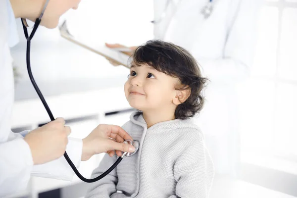 Mujer-médico examinando a un niño paciente por estetoscopio. Lindo niño árabe en la cita con el médico. Concepto de medicina — Foto de Stock