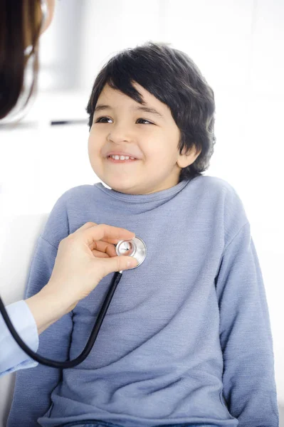 Médico-mujer examinando a un niño paciente por estetoscopio. Lindo chico árabe en la cita con el médico. Concepto de medicina — Foto de Stock