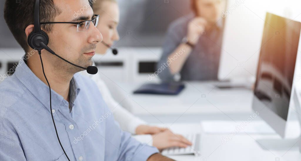 Call center. Group of casual dressed operators at work. Adult businessman in headset at customer service office. Telesales in business