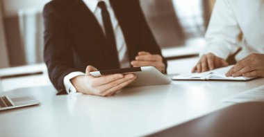 Bilinmeyen iş adamları modern ofiste tablet bilgisayar kullanıyorlar. İş adamı ya da erkek girişimci, çalışma masasında meslektaşıyla birlikte çalışıyor.