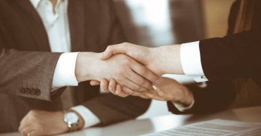 Bilinmeyen işadamı, modern ofiste iş arkadaşı ya da ortağıyla el sıkışıyor. Toplantıda iş adamları grubu