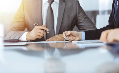 Bilinmeyen iş adamları modern ofiste birlikte çalışıyorlar, yakın plan. İş adamı ve kadın iş arkadaşları veya avukatlarıyla pazarlıkta sözleşmeyi tartışıyor