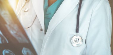 Güneşli klinikte ayakta duran ve röntgen çeken kimliği belirsiz kadın doktor.