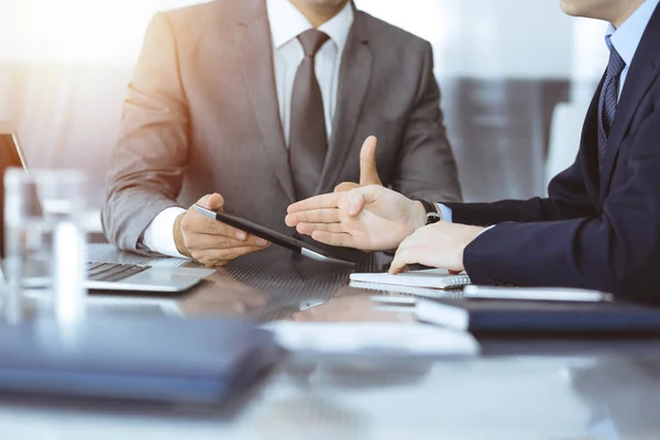 Hombre de negocios desconocido que utiliza la computadora de la tableta y el trabajo junto con su colega mientras se sienta en el escritorio de cristal en la oficina moderna. Trabajo en equipo y concepto de asociación — Foto de Stock