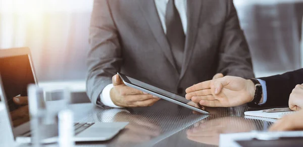 Hombre de negocios desconocido que utiliza la computadora de la tableta y el trabajo junto con su colega mientras se sienta en el escritorio de cristal en la oficina moderna. Trabajo en equipo y concepto de asociación — Foto de Stock