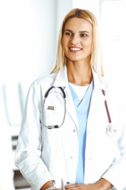 Sunny Hastanesi 'ndeki kadın doktor kadın hastaya danışmaktan mutluluk duyar. Sarışın doktor, pano kullanırken tıbbi geçmişi ve sınav sonuçlarını kontrol ediyor.