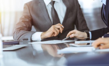 Bilinmeyen iş adamları modern ofiste birlikte çalışıyorlar, yakın plan. İş adamı ve kadın iş arkadaşları veya avukatlarıyla pazarlıkta sözleşmeyi tartışıyor