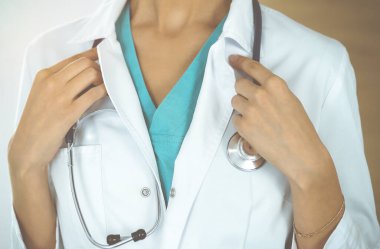 Güneşli klinikte steteskopla dikilen kimliği belirsiz kadın doktor, yakın plan.