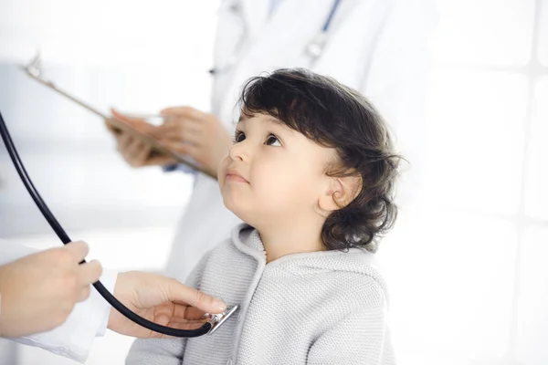 Mujer-médico examinando a un niño paciente por estetoscopio. Lindo niño árabe en la cita con el médico. Concepto de medicina — Foto de Stock