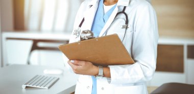 Güneşli klinikte bilinmeyen bir kadın doktor. Kadın doktor tıbbi geçmişi kontrol ediyor, yakın plan. Tıp konsepti