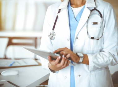 Güneşli klinikte bilinmeyen bir kadın doktor. Tablet bilgisayar kullanan kadın doktor, yakın plan.