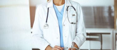 Güneşli klinikte kadın hastayla iletişim kuran kimliği belirsiz kadın doktor. Doktor tıbbi geçmişi ve sınav sonuçlarını yakından kontrol ediyor.