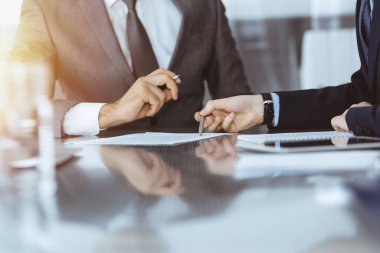 Bilinmeyen iş adamları modern ofiste birlikte çalışıyorlar, yakın plan. İş adamı ve kadın iş arkadaşları veya avukatlarıyla pazarlıkta sözleşmeyi tartışıyor