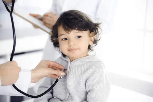 Vrouwendokter die een kindpatiënt onderzoekt met stethoscoop. Leuke Arabische peuter op afspraak bij de dokter. Geneesmiddelenconcept — Stockfoto