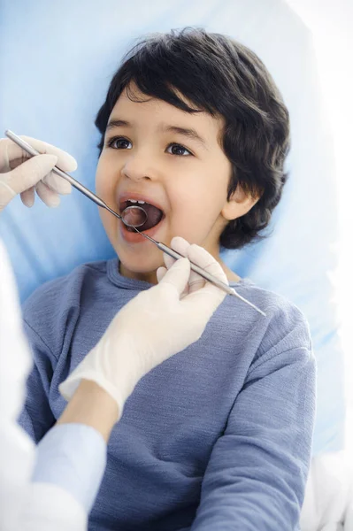 Küçük Arap çocuk dişçi doktoruna sözlü muayene sırasında ağzı açık bir şekilde dişçi koltuğunda oturuyor. Stomatoloji kavramı — Stok fotoğraf