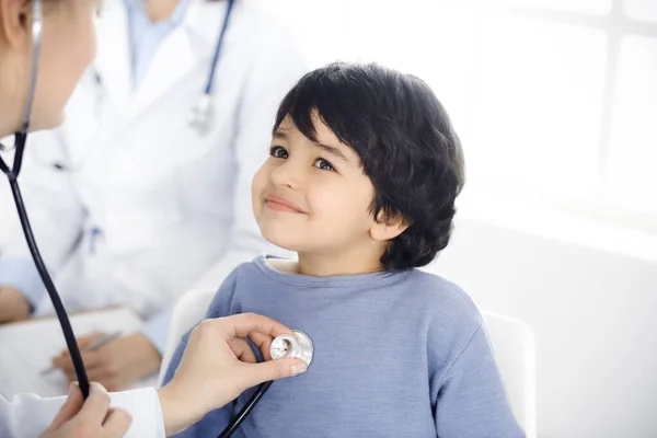 Médico-mujer examinando a un niño paciente por estetoscopio. Lindo chico árabe en la cita con el médico. Concepto de medicina — Foto de Stock