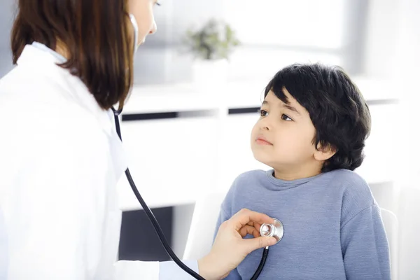 Médico-mujer examinando a un niño paciente por estetoscopio. Lindo chico árabe en la cita con el médico. Concepto de medicina — Foto de Stock