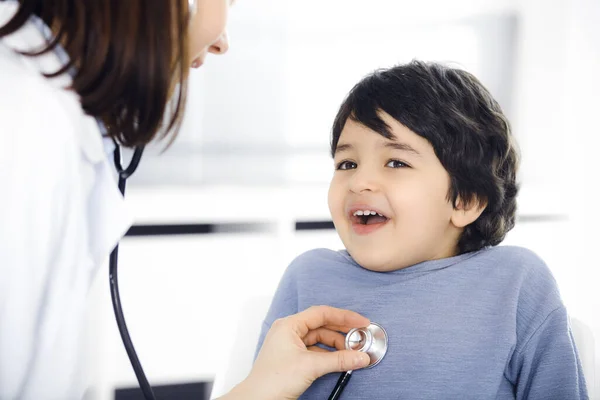 Docteur-femme examinant un enfant patient par stéthoscope. Joli garçon arabe sur rendez-vous chez le médecin. Concept de médecine — Photo