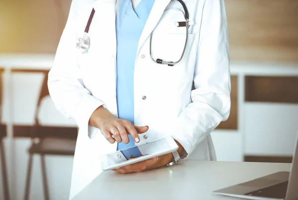 Άγνωστη γυναίκα-γιατρός στη δουλειά στην ηλιόλουστη κλινική. Γυναίκα ιατρός που χρησιμοποιεί τον υπολογιστή του δισκίου, κοντινό πλάνο — Φωτογραφία Αρχείου