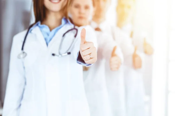Bir grup modern doktor güneşli hastanede baş parmakları havada bir takım olarak ayakta duruyor. Tıbbi yardım, sağlık sigortası, en iyi hastalık tedavisi ve ilaç konsepti — Stok fotoğraf
