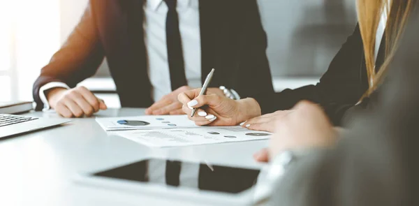 Uomini d'affari e donne sconosciuti seduti, che lavorano e discutono domande all'incontro in ufficio soleggiato, primo piano. Concetto di successo — Foto Stock