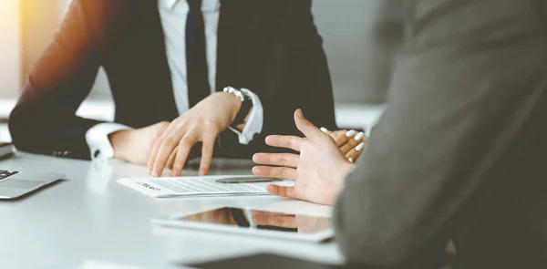 Empresarios y mujeres desconocidos sentados, usando computadora portátil y discutiendo preguntas en la reunión en la oficina soleada, de cerca. Concepto de éxito — Foto de Stock