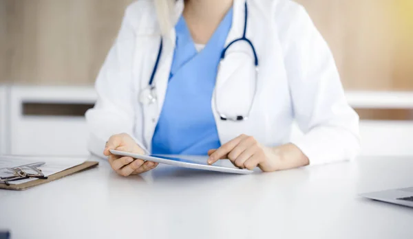 Άγνωστη γυναίκα-γιατρός κάθεται σε ηλιόλουστη κλινική και χρησιμοποιώντας το tablet pc, close-up. Δεδομένα και καλύτερη εξυπηρέτηση στην ιατρική — Φωτογραφία Αρχείου