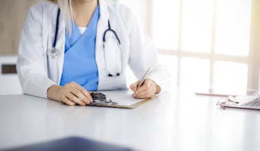 Sunny Kliniği 'nde tıbbi geçmişi dolduran kimliği belirsiz kadın doktor, yakın plan.