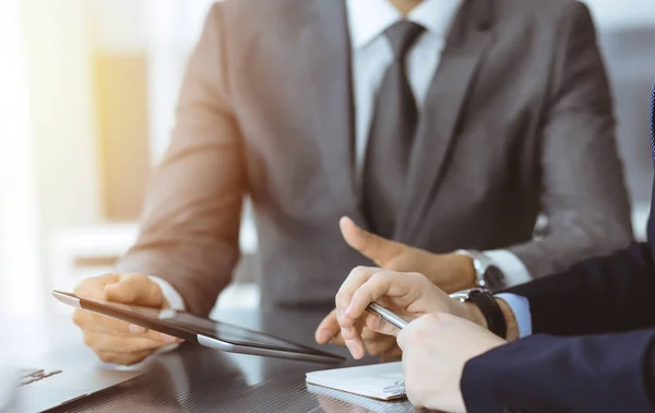 Hombre de negocios desconocido que utiliza la computadora de la tableta y el trabajo junto con su colega mientras se sienta en el escritorio de cristal en la oficina moderna. Trabajo en equipo y concepto de asociación — Foto de Stock