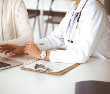 Bilinmeyen kadın doktor oturuyor ve kadın hastayla iletişim kuruyor. Doktor tıbbi geçmişi ve muayene sonuçlarını yakından kontrol ediyor. Sağlık hizmetleri kavramı