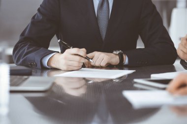 Bilinmeyen iş adamları modern ofiste birlikte çalışıyorlar, yakın plan. İş adamı ve kadın iş arkadaşları veya avukatlarıyla pazarlıkta sözleşmeyi tartışıyor