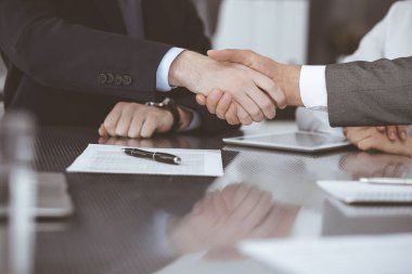 Başarılı bir müzakere olarak tokalaşma, yakın plan. Modern ofiste kontrat imzaladıktan sonra bilinmeyen iş adamları el sıkışıyor