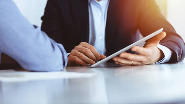 Gente de negocios que usa tableta mientras trabajan juntos en la soleada oficina moderna. Hombre de negocios desconocido con colega en el lugar de trabajo. Trabajo en equipo y concepto de asociación — Foto de Stock