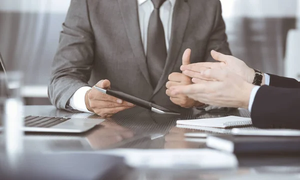 Hombre de negocios desconocido que utiliza la computadora de la tableta y el trabajo junto con su colega mientras se sienta en el escritorio de cristal en la oficina moderna. Trabajo en equipo y concepto de asociación — Foto de Stock