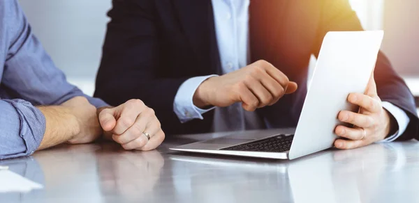 Gente de negocios usando computadora portátil mientras trabajan juntos en la soleada oficina moderna. Hombre de negocios desconocido con colega en el lugar de trabajo. Trabajo en equipo y concepto de asociación Imagen de stock