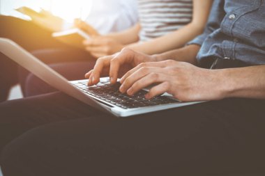 Bir grup sıradan giyimli iş adamı güneşli ofiste toplantı ya da konferansta çalışıyor, yakın çekim. Dizüstü bilgisayar kullanan bir iş adamı