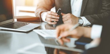 Bilinmeyen iş adamları ve kadınlar oturuyor, dizüstü bilgisayar kullanıyorlar ve güneşli ofiste soruları tartışıyorlar, yakın plan. Başarı konsepti