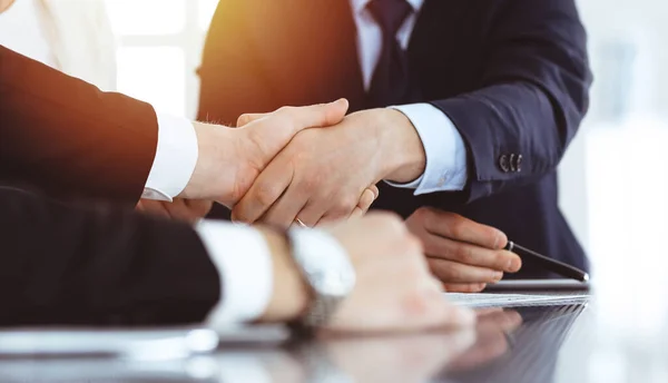 Zakenmensen schudden elkaar de hand na het tekenen van een contract in het zonnige moderne kantoor. Teamwork en handdruk concept — Stockfoto
