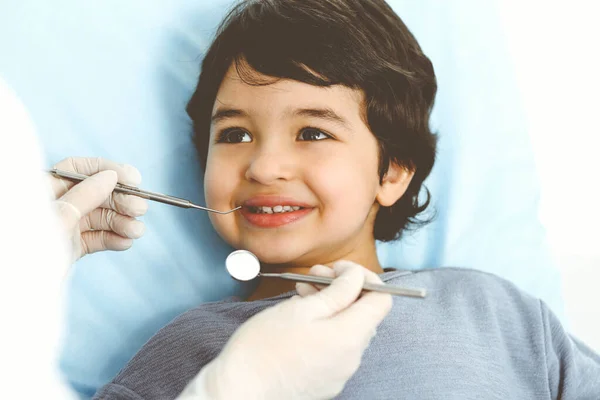 Netter arabischer Junge sitzt auf dem Zahnarztstuhl mit offenem Mund während der Oraluntersuchung beim Arzt. Zahnarztbesuche. Stomatologisches Konzept — Stockfoto