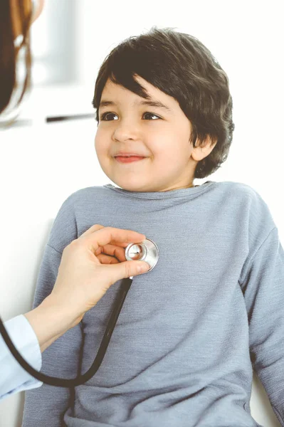 Médico-mujer examinando a un niño paciente por estetoscopio. Lindo chico árabe en la cita con el médico. Concepto de medicina — Foto de Stock