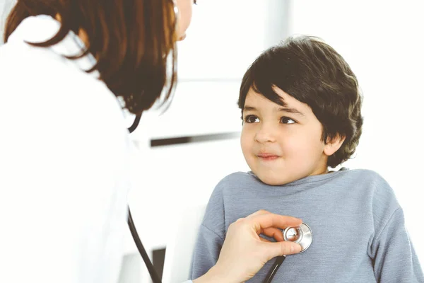 Ärztin untersucht eine Kinderpatientin mit einem Stethoskop. Netter arabischer Junge beim Arzttermin. Medizinkonzept — Stockfoto