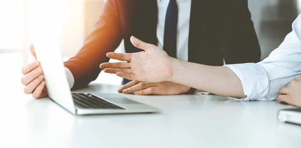 Empresarios y mujeres desconocidos sentados, usando computadora portátil y discutiendo preguntas en la reunión en la oficina soleada, de cerca. Concepto de éxito — Foto de Stock