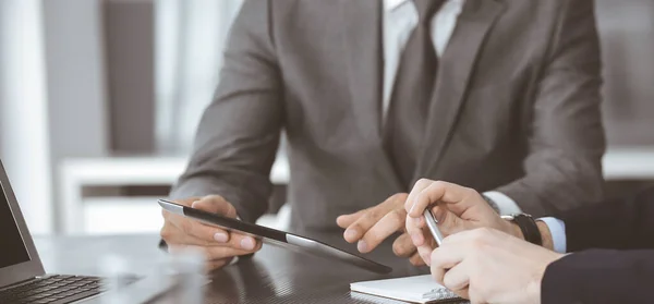 Hombre de negocios desconocido que utiliza la computadora de la tableta y el trabajo junto con su colega mientras se sienta en el escritorio de cristal en la oficina moderna. Trabajo en equipo y concepto de asociación — Foto de Stock