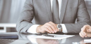 Bilinmeyen iş adamları modern ofiste birlikte çalışıyorlar, yakın plan. İş adamı ve kadın iş arkadaşları veya avukatlarıyla pazarlıkta sözleşmeyi tartışıyor